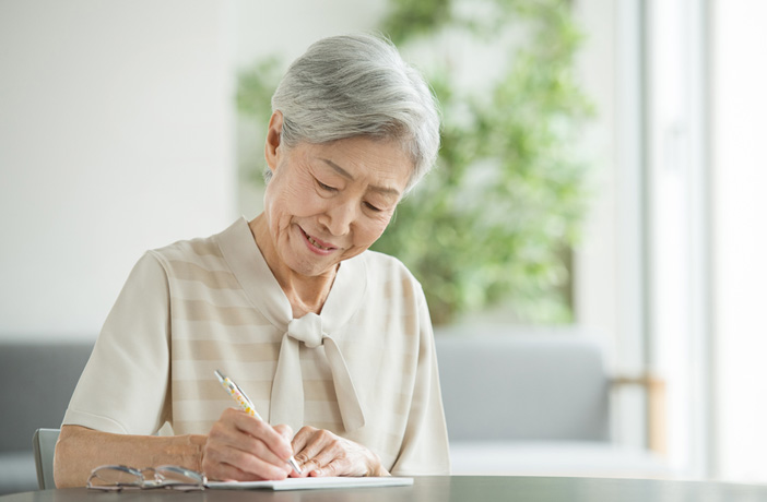 手紙を書く高齢者の女性