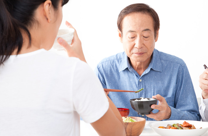 家族と食事を食べる高齢者の男性